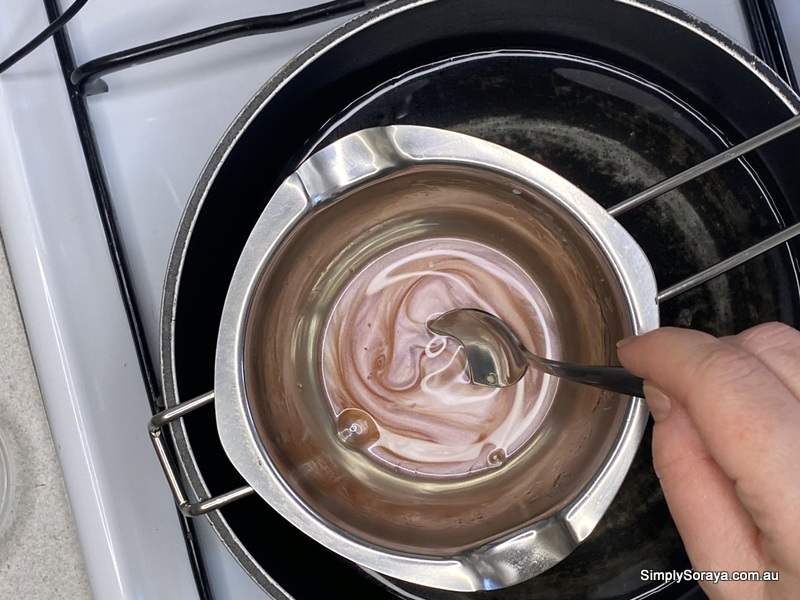 Mixing in the pink mica into lip balm with cocoa butter